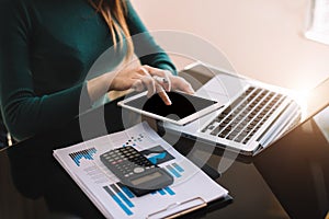 Businesswoman or Designer using tablet with laptop and document on desk.