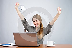 Businesswoman at desk with arms thrown up