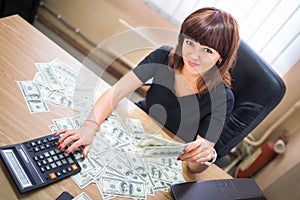 Businesswoman at the desk holds bribe money