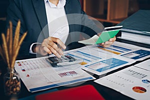 Businesswoman on desk in office using calculator to calculate sa