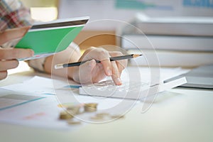 Businesswoman on desk in office using calculator to calculate saving account passbook and statement with financial report .Female