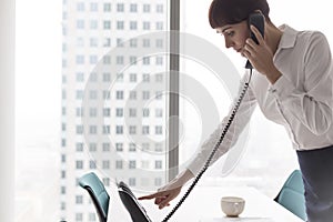 Businesswoman dialing on landline phone at office
