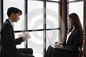 Business woman with disability using laptop computer and analyzing statistical graph with colleague.