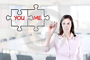 Businesswoman drawing a You and Me puzzle love concept on the virtual screen. Office background.
