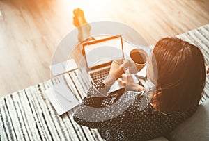 Businesswoman dressed in pajamas enjoying morning coffee on the floor office with laptop, papers top view shot. Distance