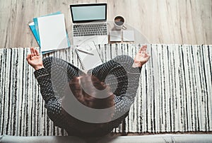 Businesswoman dressed in pajamas meditating with morning coffee with Gyan Mudra palms.On the floor office with laptop, papers top