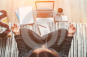 Businesswoman dressed in pajamas meditating with morning coffee with Gyan Mudra palms.On the floor office with laptop, papers top