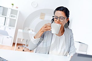 Businesswoman drinking coffee or tea at office