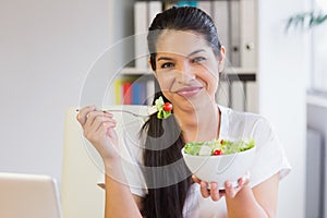 Businesswoman eating salad in office