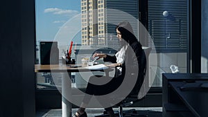 Businesswoman eating at workplace.Young woman in a modern beautiful office near the panoramic window dines and examines