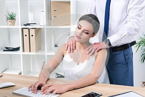 Businesswoman enjoying massage from her colleague while working