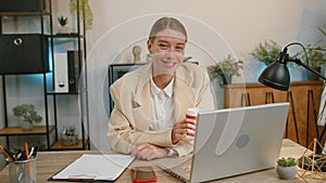 Businesswoman enters office start working on laptop computer at desk and drinking morning coffee