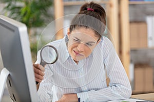 businesswoman examining contract meticulously with magnifying glass