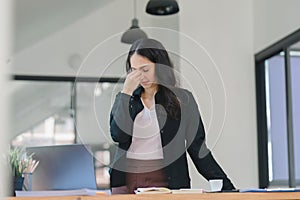 Businesswoman is experiencing a headache and fatigue while working in the office, possibly due to eye strain from