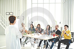 Businesswoman explain ideas to group of creative diverse team at modern office. Rear view of manager gesturing hand standing again