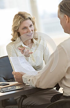 Businesswoman Explaining Report To Colleague In Office