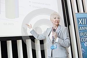 Businesswoman explaining strategy on projection screen at convention center