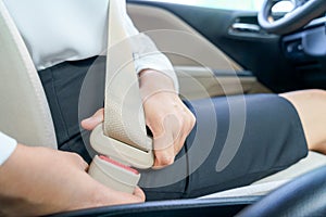 Businesswoman fastening seat belt in car before driving.