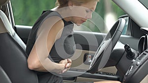 Businesswoman feeling abdominal pain, sitting in car, indigestion discomfort