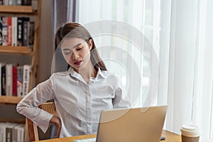 Businesswoman feeling pain in spine back after sedentary computer work sitting in bad posture in office