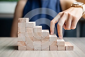 Businesswoman finger step on wooden block building