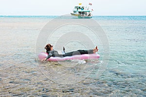 Businesswoman floating on lilo in sea with laptop