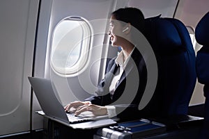 businesswoman flying and working in an airplane in first class, businesswoman sitting inside an airplane using laptop