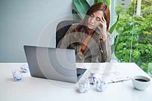 Businesswoman get stressed with screwed up papers and laptop on table while having a problem at work