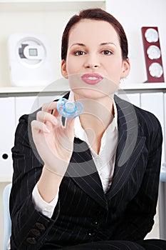 Businesswoman giving a baby`s dummy to her child.