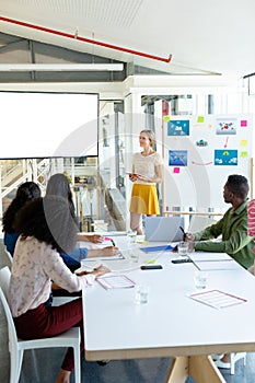 Businesswoman giving presentation on screen during meeting in a modern office
