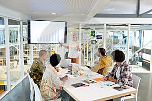 Businesswoman giving presentation on screen during meeting in a modern office