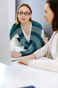 Businesswoman giving presentation to her female colleague while they sitting at the desk with computer. Group of