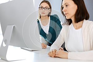 Businesswoman giving presentation to her female colleague while they sitting at the desk with computer. Group of