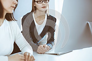 Businesswoman giving presentation to her female colleague while they sitting at the desk with computer. Group of