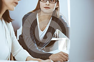 Businesswoman giving presentation to her female colleague while they sitting at the desk with computer. Group of