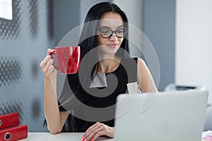 Businesswoman in glasses with a cup of coffee in the office