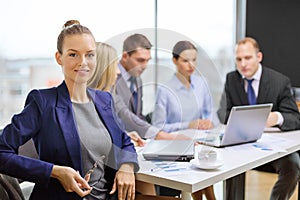 Businesswoman with glasses with team on the back