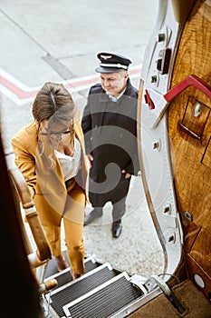 Businesswoman going up on ladder of airplane