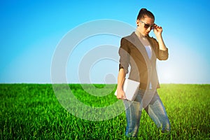 businesswoman in a green field with a laptop