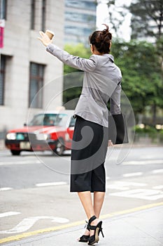 Businesswoman Hailing Taxi In Busy Street photo