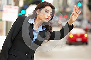 Businesswoman Hailing Taxi In Busy Street photo