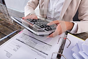 Businesswoman Hand Calculating Invoice Using Calculator