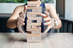 Businesswoman hand cover wooden block on the tower