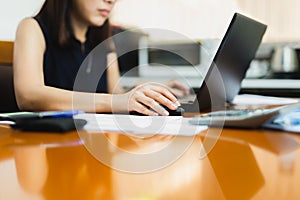 Businesswoman hand holding computer mouse working on wooden desk.