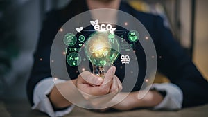 Businesswoman hand holding light bulb with ESG icon on virtual screen, ESG Environmental, social and corporate governance concept