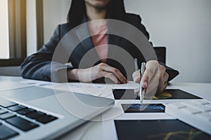 Businesswoman hand holding pen, analysis the graph with calculartor and laptop at the home office for setting challenging business