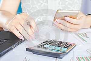 Businesswoman hand holding smart phone and working on financial graph report