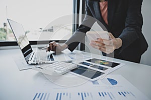 Businesswoman hand holding smartphone, analysis the graph with calculartor and laptop at the home office for setting challenging