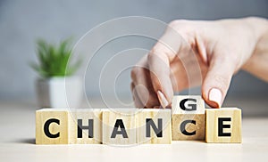 Businesswoman hand holding wooden cube with flip over block CHANGE to CHANCE word on table background. success, strategy