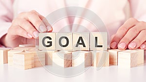 Businesswoman hand holding wooden cube with GOAL text on table background. Goals, success, strategy, solution and